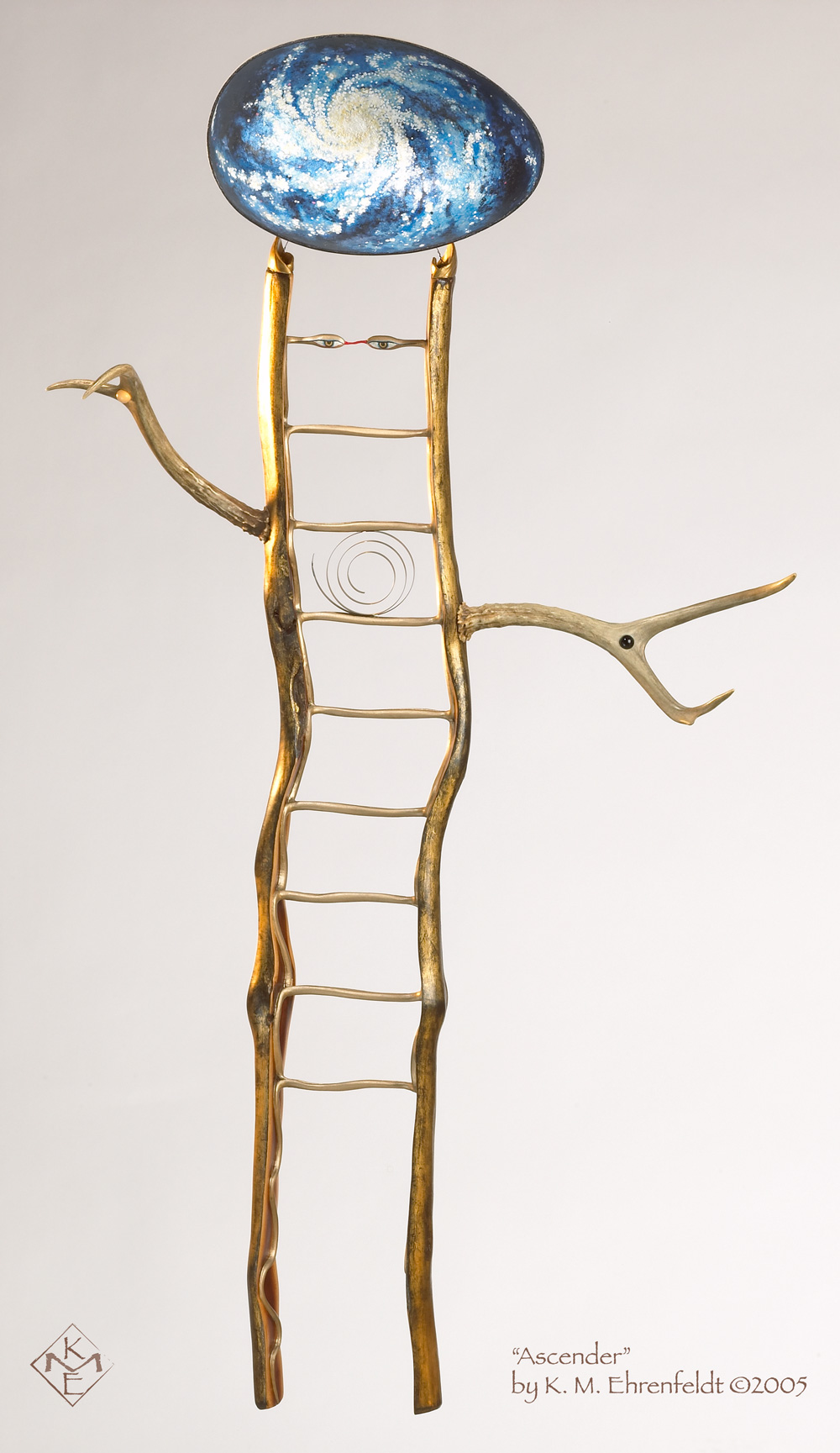 The ladder-like form of this being has an undulating essence that holds up the heavens. The madrone wood appears split down its length to reveal the heartwood, where two gold-leafed snakes carved into the ladder cross back and forth to form the rungs that rising from knee length to the area of the head. There, snake heads meet as eyes that appear like the calmly lidded Sipa Barda's. Vibrant snake tongues bridge across to connect the eyes together. The outer wood of ladder is gold leaf, culminating in feline shaped ears. These ear points hold up a convex cosmic egg containing a painted spiral galaxy in shimmering silver leaf, pale golds, and blues. In the center of the ladder body is a delicate brass spiral, positioned in an active spiral direction. To the left and right are pronghorn antlers reaching outward as arms. In its right arm, rising upward, is held a moonstone cabochon, and in its left arm reaching outward to the side, is held an onyx cabochon.