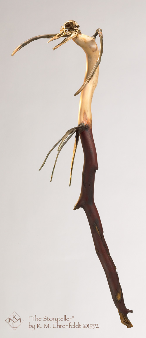 The curving madrone wood stick has the deep red-brown, smooth, skin-line bark on the lower half, and has the creamy-colored heart wood visible for the upper half. The upper half serves as the body of the Storyteller bird's skeletal shape. The head is an actual bird skull with a long open-mouthed beak, it has a bronze-hued finish, with coiled copper at the neckline. At the curved shoulder of the stick, two bronze, bone-like, wing appendages reach outward. The body has been lightly wood burned to form delicate tattoo designs spiraling down the body from the neckline. Four bronze bone-like tail feathers jut out at the base of the body where the madrone bark begins. The lower half of the stick culminates in a naturally weathered break that is a reaching hand shape.