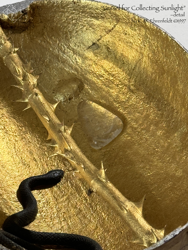 The Sun Vessel in partial view reveals its gold-leafed interior with a thorny gold-leafed rose stem bisecting the gourd lengthwise across the top from stem to base. A black snake enters from the lower left curving across the bottom toward the center. On the opposite side of the thorny rod above, a clear glass triangle rests inside, pointing upward, and resembles a puddle of light. A raised bump is visible above the puddle of light. The rim of the vessel is a deep blue and silver.